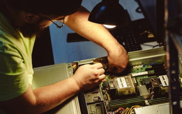 Man repairing a computer server under a lamp.